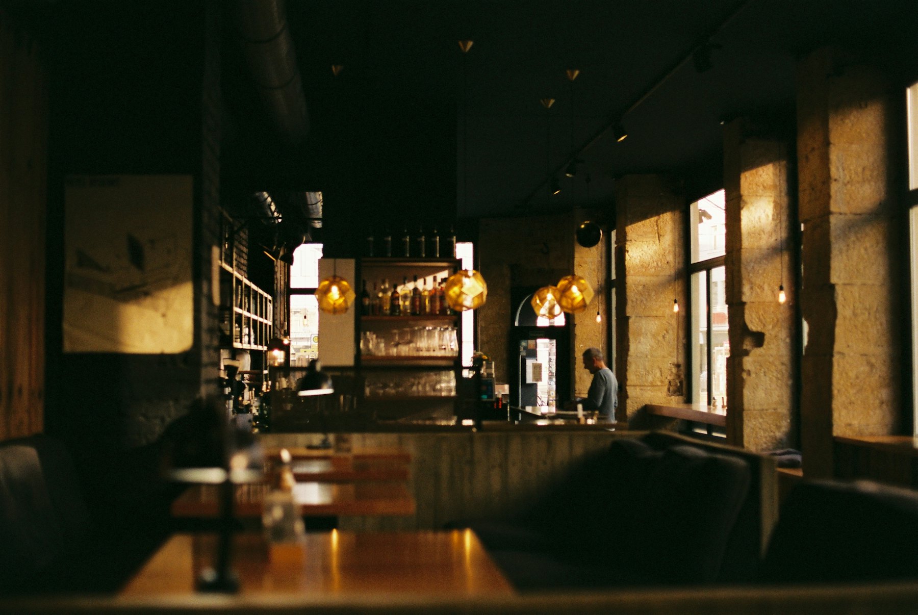 Salle du bistrot en fin de journée, comptoir et suspensions allumées